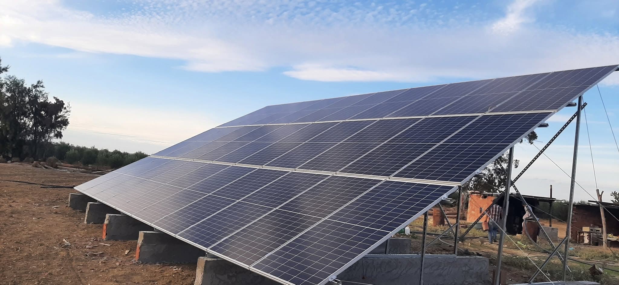 Panneaux solaires photovoltaïques sur une structure métallique dans un champ sous un ciel bleu.