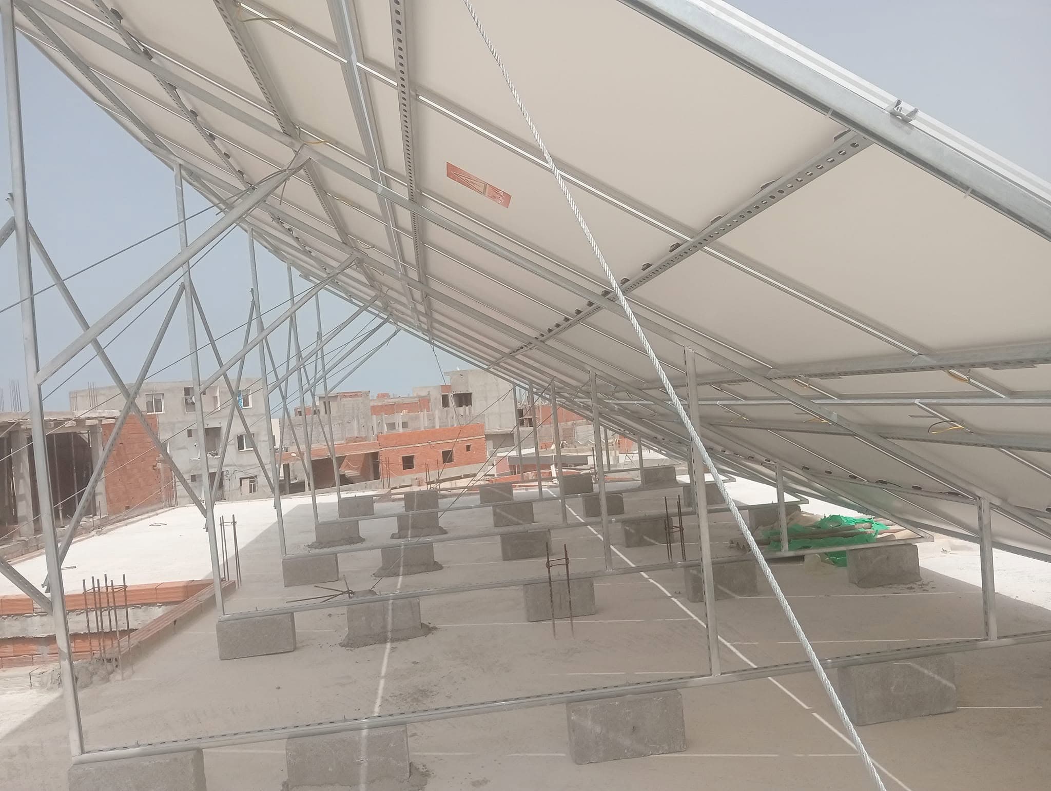Structure métallique et blocs de béton sous des panneaux solaires sur un toit en ville.